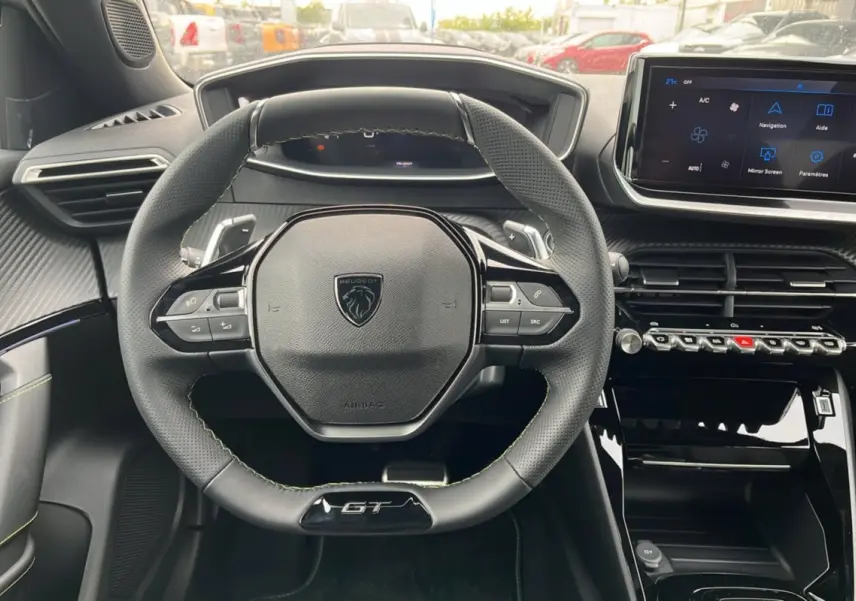 Vue intérieure centrée sur le volant GT du Peugeot 2008 Hybrid 145, avec tableau de bord numérique et écran tactile.