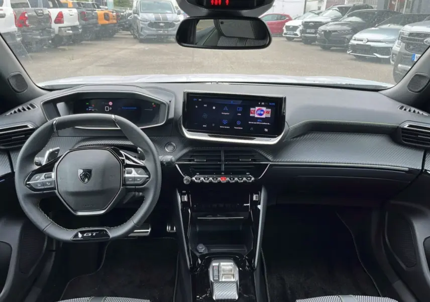 Intérieur moderne du Peugeot 2008 Hybrid 145 GT Vision 2025, tableau de bord et volant compact avec finitions carbone.
