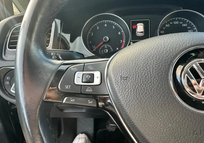 Gros plan sur le volant multifonctions noir de la Volkswagen Golf 1.5 TSI 2018 avec tableau de bord et commandes visibles.