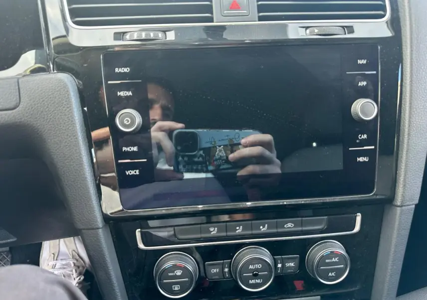 Vue rapprochée du tableau de bord noir de la Volkswagen Golf 1.5 TSI 2018 avec écran tactile et commandes climatisation.