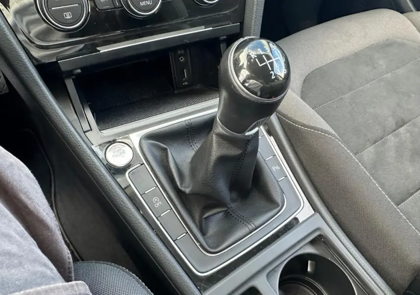 Gros plan sur la commande de boîte manuelle noire et la console centrale de la Volkswagen Golf 2018, sièges gris.