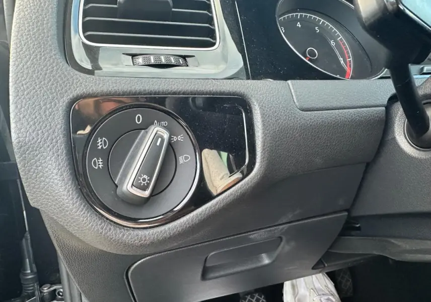 Gros plan sur la commande des phares à gauche du tableau de bord d'une Volkswagen Golf noire de 2018.