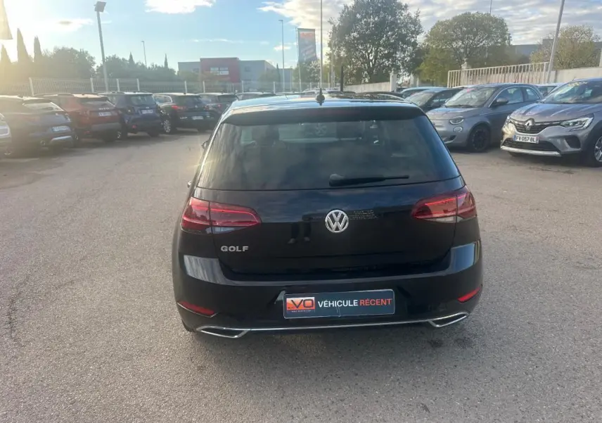 Vue arrière d'une Volkswagen Golf noire 2018 avec feux rouges et double sortie d'échappement chromée.