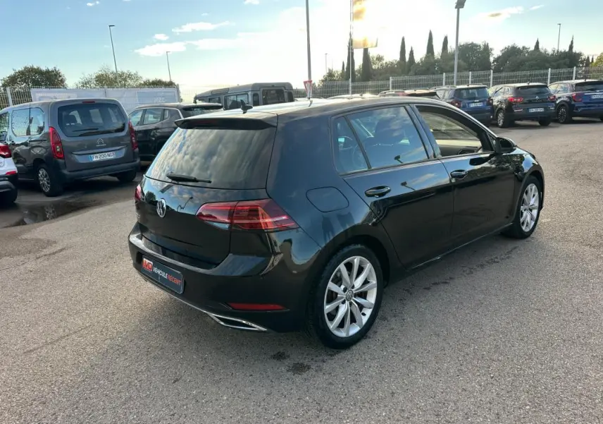 Volkswagen Golf noire vue en 3/4 arrière droit, avec jantes alliage 17 pouces et vitres teintées.