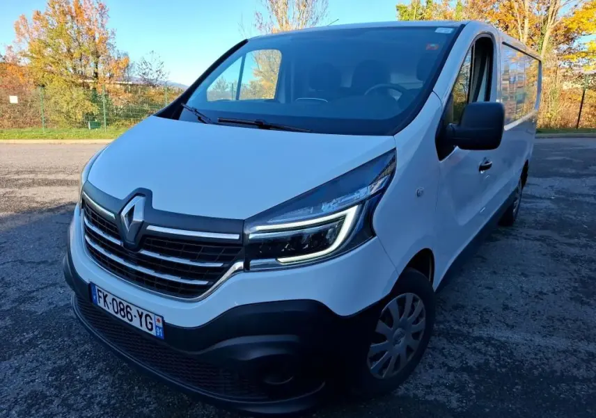 Renault Trafic Fourgon blanc vu en 3/4 avant droit, avec calandre noire et phares LED allumés.