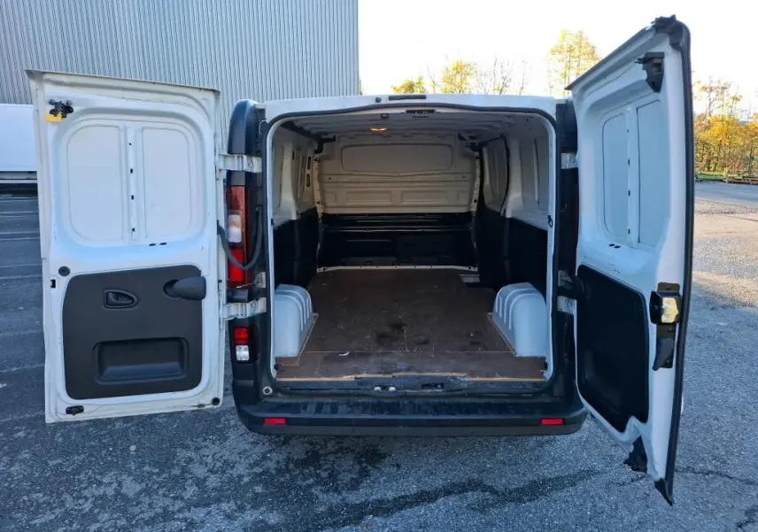 Vue arrière ouverte du Renault Trafic Fourgon blanc L2H1 2019 montrant l'espace de chargement vide avec plancher en bois.