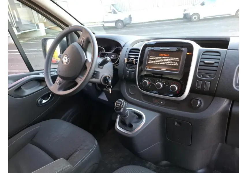 Vue intérieure côté conducteur du Renault Trafic Fourgon 2019, montrant le volant, levier de vitesses manuel et écran tactile central.