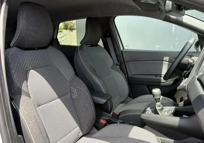 Vue intérieure côté conducteur du Renault Captur TCE 90 Techno 2025, sièges tissu gris avec surpiqûres contrastées.