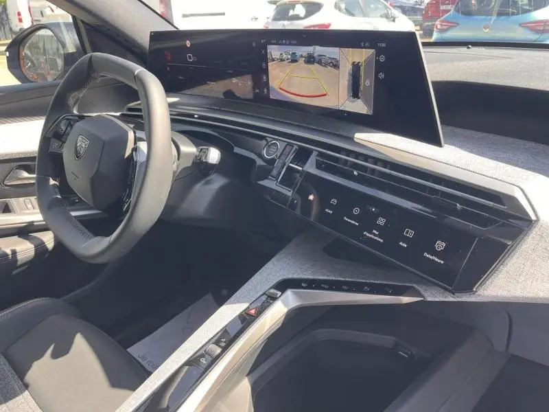 Vue intérieure côté conducteur du Peugeot 5008 Hybrid blanc, avec tableau de bord numérique et écran tactile central affichant la caméra de recul.