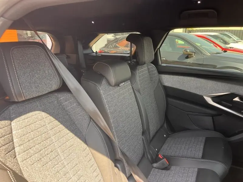Vue intérieure côté droit des sièges arrière du Peugeot 5008 Hybrid blanc, avec tissu gris et coutures apparentes.