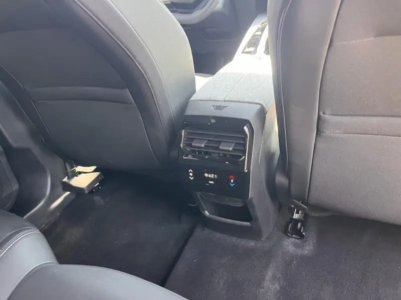Vue rapprochée de la console centrale arrière noire entre les sièges avant gris foncé du Peugeot 5008 Hybrid 2025.