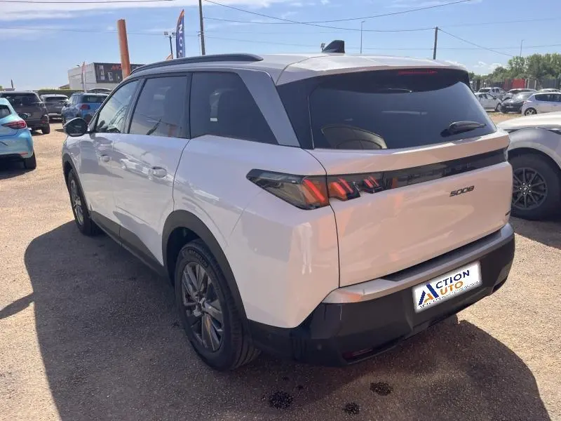 Vue 3/4 arrière droite d’un Peugeot 5008 blanc Okénite avec vitres surteintées et feux arrière LED distinctifs.