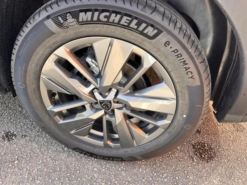 Gros plan sur la jante alu grise et le pneu Michelin e.Primacy du Peugeot 5008 Hybrid blanc Okénite.