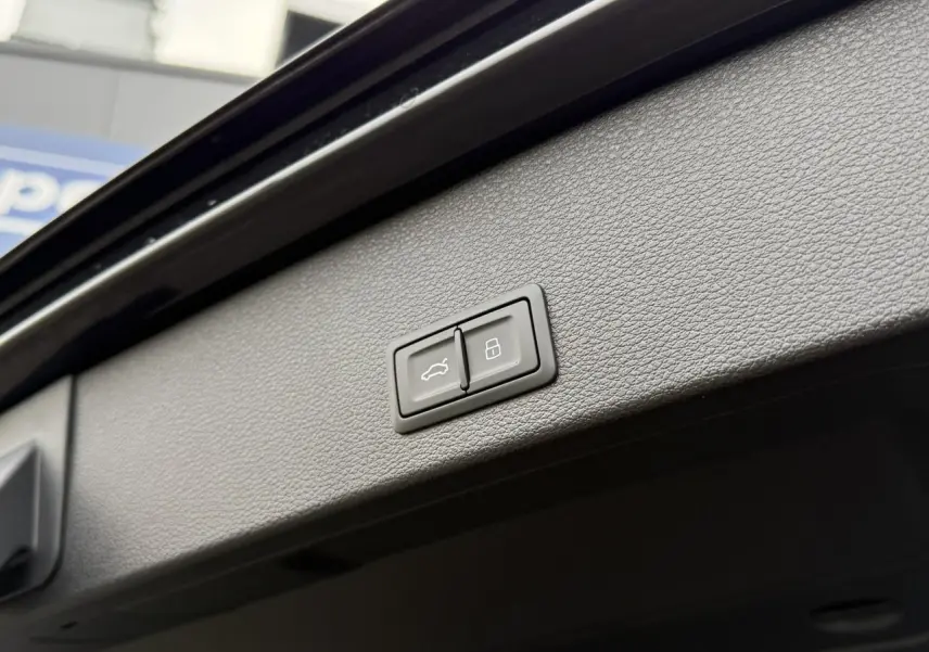 Boutons de commande du hayon électrique et de verrouillage sur le panneau intérieur du coffre d'un Audi Q2 noir Mythe.