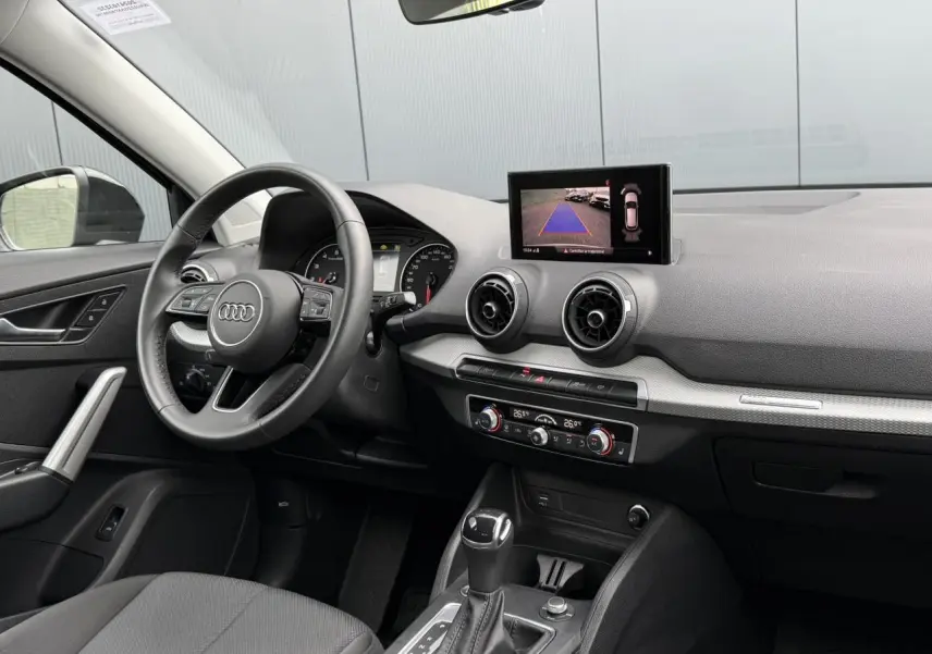 Vue intérieure côté conducteur de l'Audi Q2 35 TFSI 2023 avec tableau de bord et écran de caméra de recul.