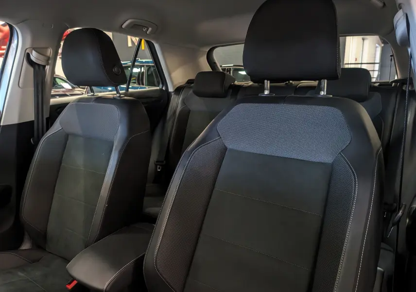 Gros plan sur les sièges avant en cuir noir et tissu gris d'un Volkswagen T-Roc 2024, intérieur spacieux et moderne.
