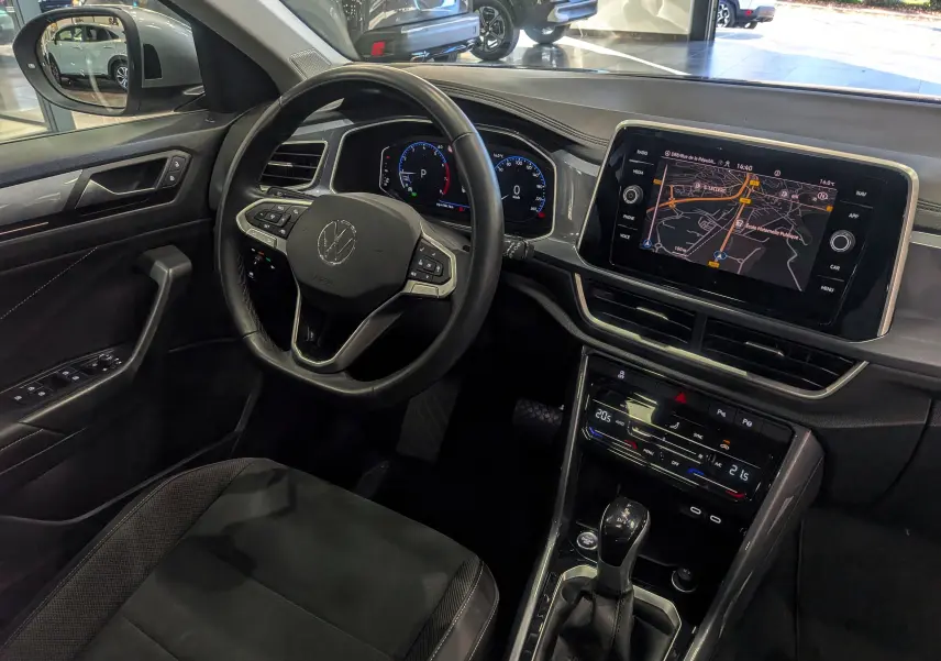 Vue intérieure côté conducteur du Volkswagen T-Roc 2024 avec tableau de bord numérique et écran tactile de navigation.