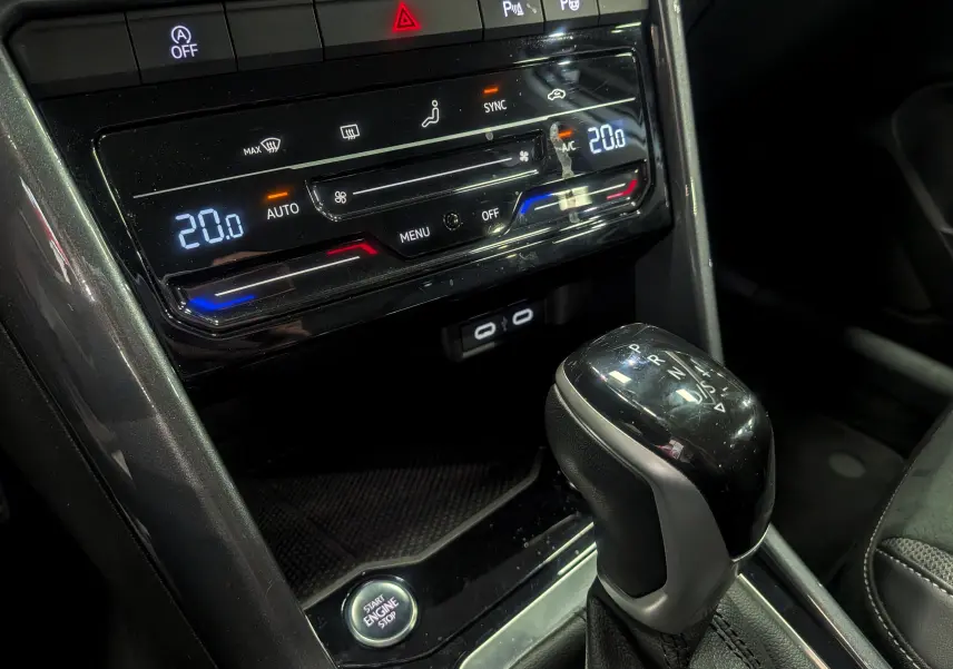 Gros plan sur la console centrale du Volkswagen T-Roc gris pyrite 2024, avec levier de vitesses automatique et commandes climatisation digitale.