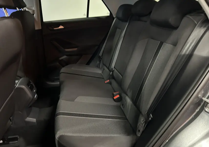 Vue intérieure des sièges arrière en tissu noir du Volkswagen T-Roc gris Indium, avec ceintures de sécurité et appuie-têtes visibles.