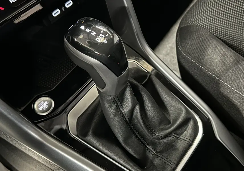 Gros plan sur le levier de vitesse automatique noir et la console centrale du Volkswagen T-Roc TSI 150 DSG gris Indium.