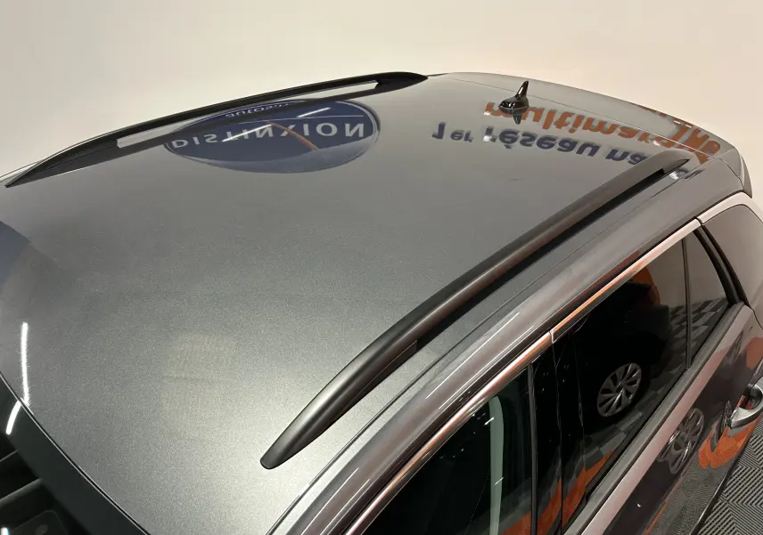 Vue en plongée du toit gris indium métallisé du Volkswagen T-Roc 2025 avec barres de toit noires et antenne requin.