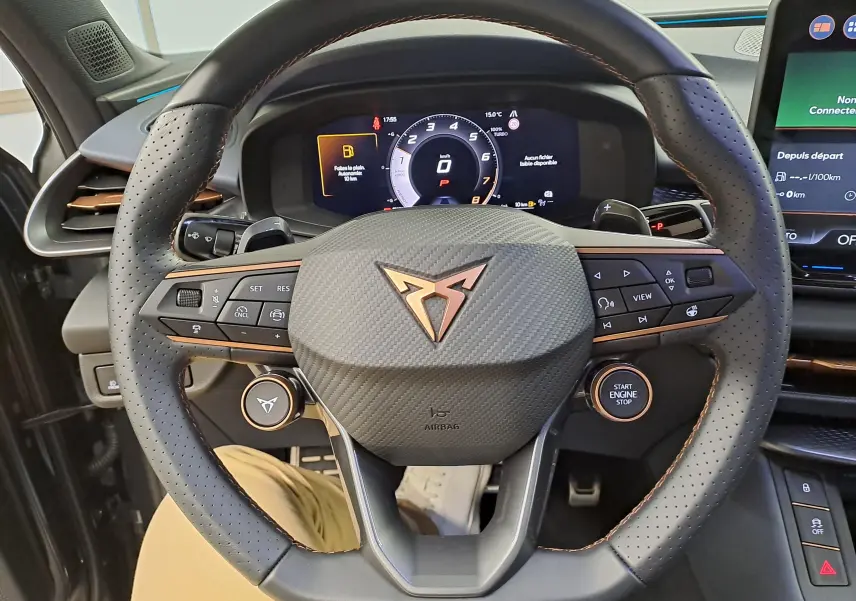 Vue rapprochée du volant perforé avec logo CUPRA cuivré et tableau de bord numérique du CUPRA TERRAMAR gris Timanfaya.