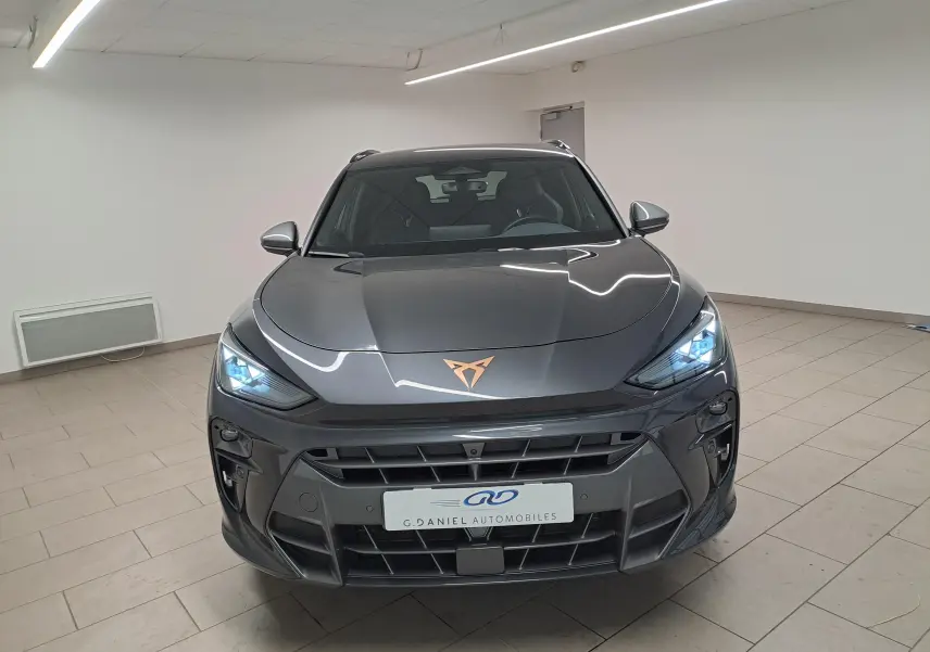 Vue frontale du CUPRA TERRAMAR gris Timanfaya avec feux allumés et logo cuivré sur le capot.