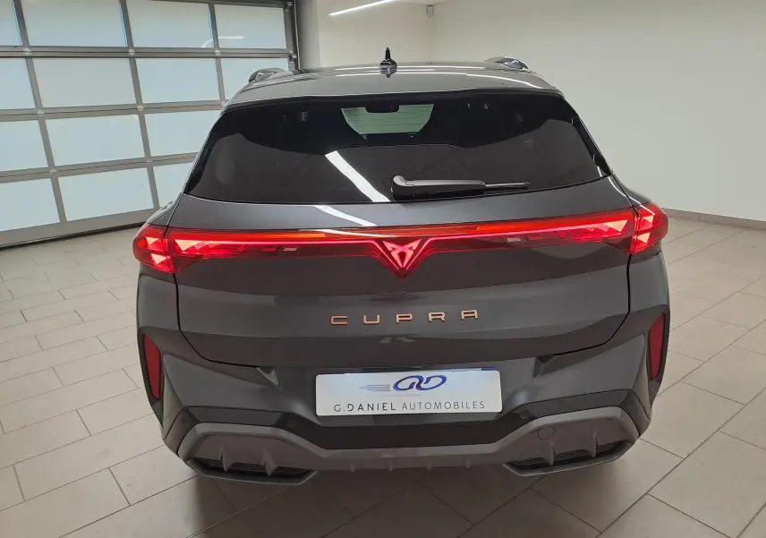 Vue arrière du CUPRA TERRAMAR gris Timanfaya avec feux arrière allumés et logo lumineux au centre.