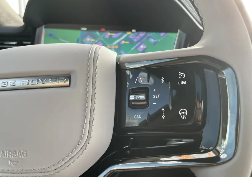 Gros plan sur le côté droit du volant beige clair du Range Rover Sport P440 HSE R-Dynamic avec commandes de régulateur adaptatif.