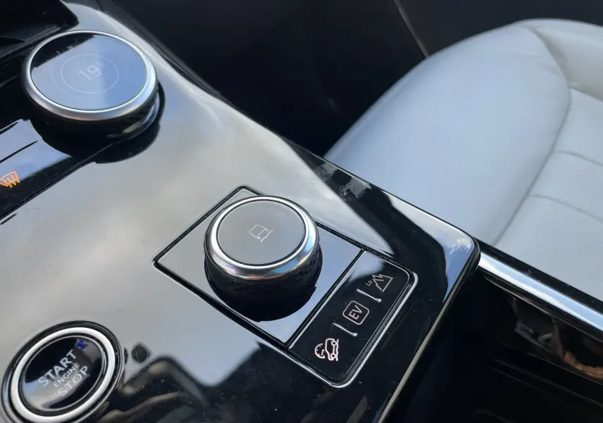 Gros plan sur la console centrale noire brillante du Range Rover Sport P440 HSE R-Dynamic 2023 avec siège cuir blanc visible.