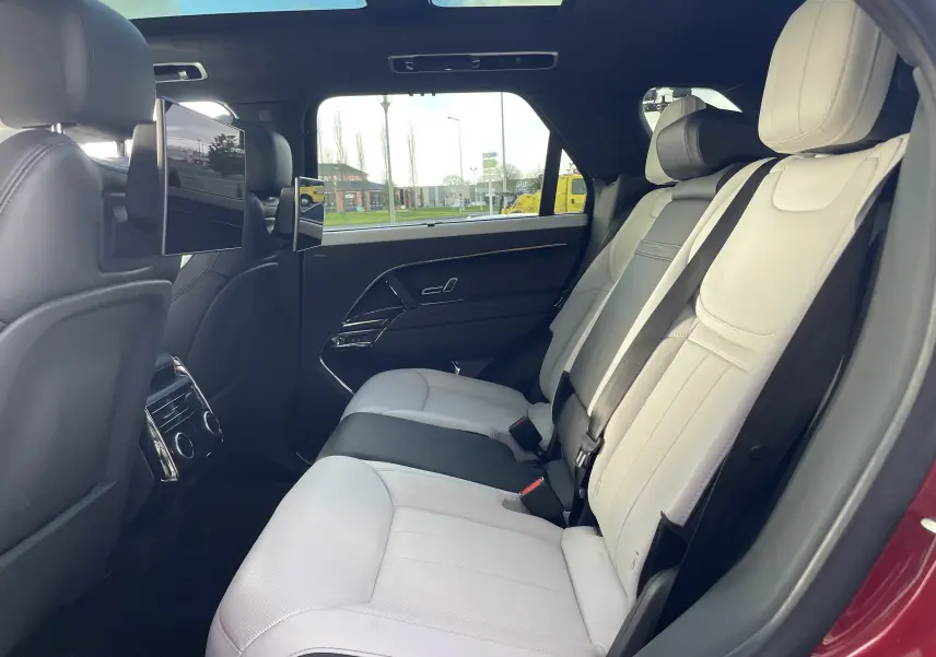 Vue intérieure côté droit des sièges arrière en cuir blanc avec écrans intégrés aux appuie-tête du Range Rover Sport P440 HSE R-Dynamic rouge.