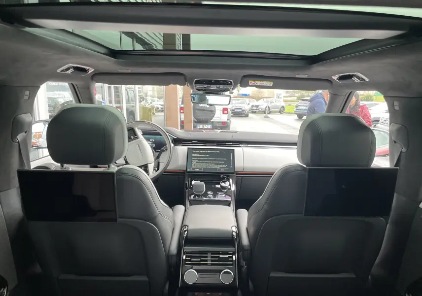 Vue intérieure arrière du Range Rover Sport P440 HSE R-Dynamic avec sièges cuir noirs et écrans intégrés aux appuie-têtes.