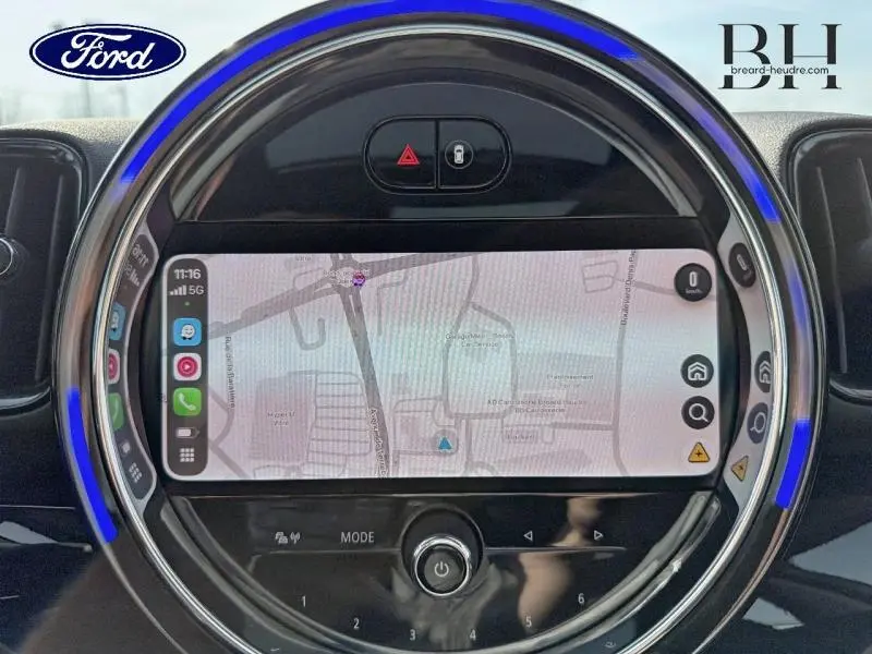 Vue rapprochée de l'écran tactile central rond du MINI Countryman Moonwalk Grey avec interface GPS et éclairage LED bleu.