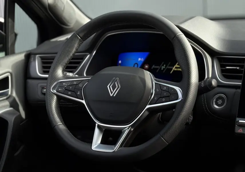 Vue rapprochée du volant noir perforé de la Renault SYMBIOZ 2025 avec commandes intégrées et tableau de bord numérique.