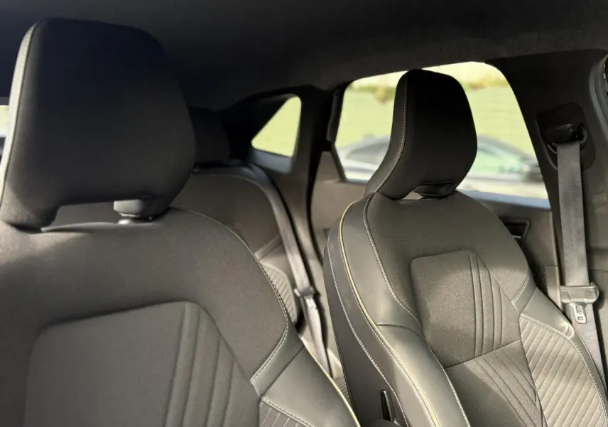 Vue intérieure des sièges avant en tissu noir et cuir avec surpiqûres contrastantes du Renault Symbioz 2025.