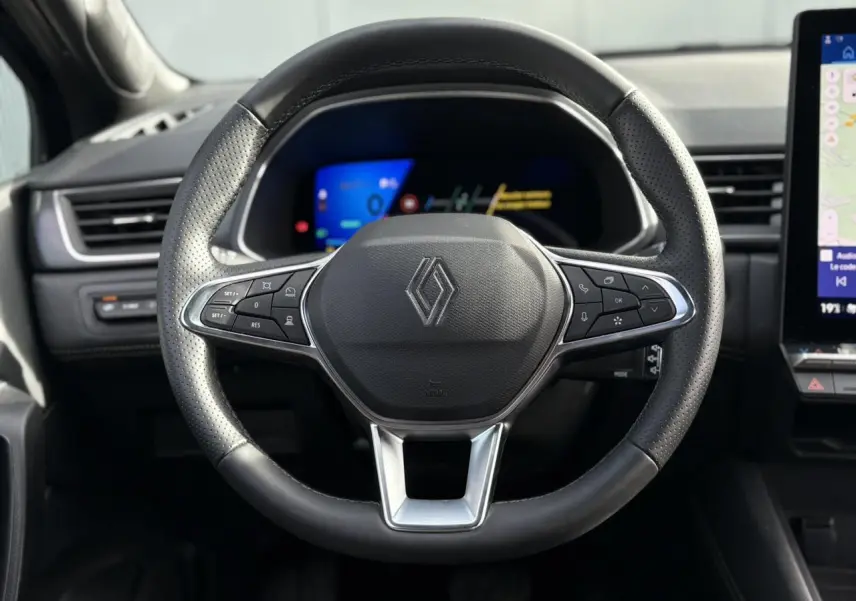 Volant en cuir noir perforé de Renault SYMBIOZ 2025 vu de face avec tableau de bord numérique en arrière-plan.
