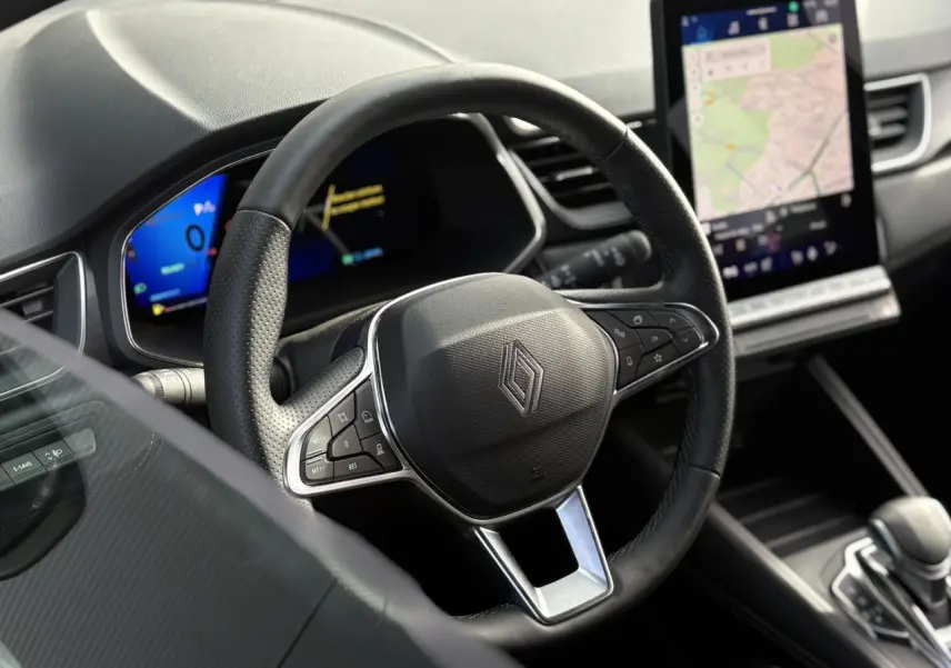 Vue intérieure centrée sur le volant noir perforé du Renault Symbioz 2025 avec écran tactile vertical et tableau de bord numérique.