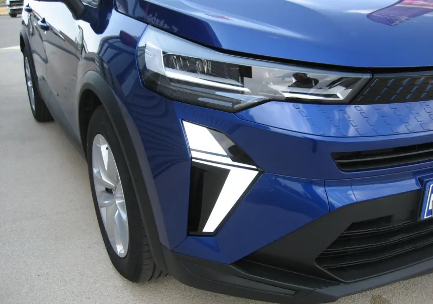 Vue 3/4 avant droit du Renault Captur II bleu iron, mettant en valeur ses phares LED et la calandre moderne.