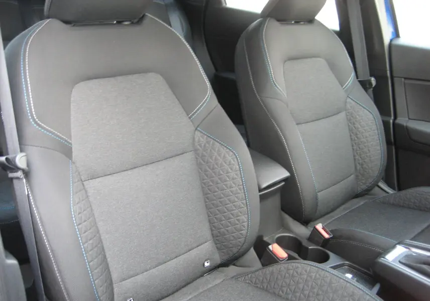 Vue rapprochée des sièges avant gris foncé avec surpiqûres bleues du Renault Captur II 1.6 E-TECH Hybride 2025.