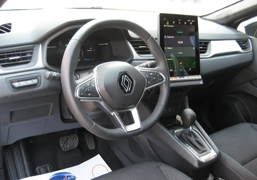 Vue intérieure du tableau de bord et volant du Renault Captur II hybride 2025, avec écran tactile vertical et levier de boîte automatique.