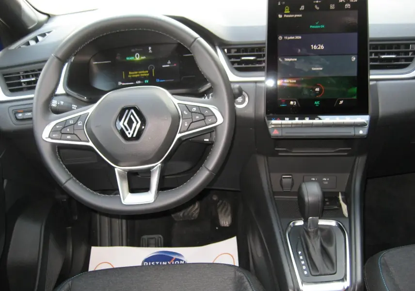 Vue intérieure frontale du tableau de bord du Renault Captur II bleu Iron, avec volant multifonction et écran tactile central allumé.