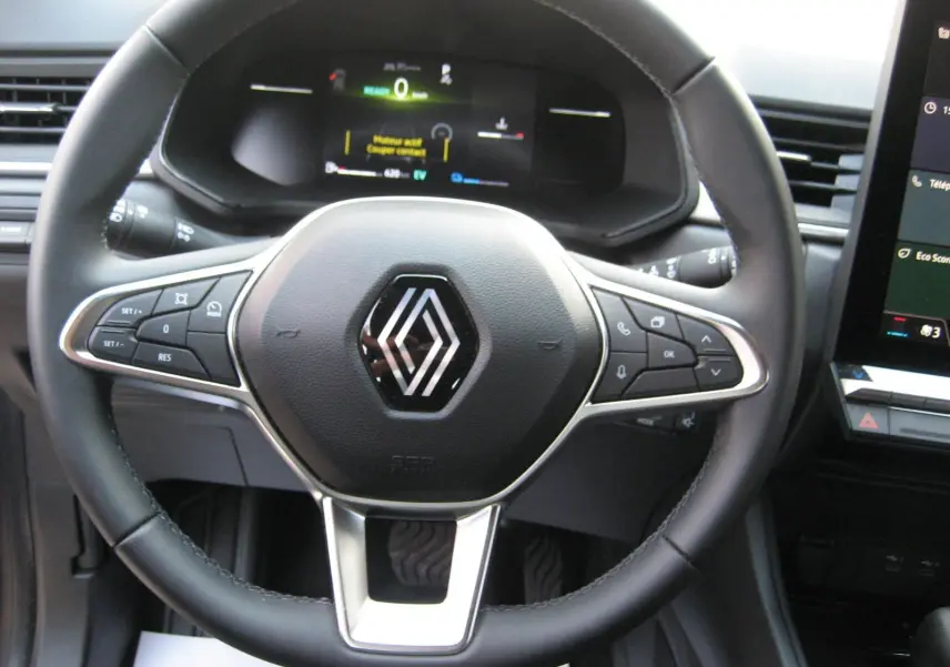 Vue rapprochée du volant noir du Renault Captur II 1.6 E-Tech Hybride 2025 avec tableau de bord numérique allumé.