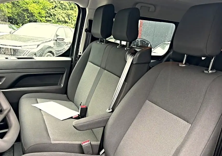 Vue intérieure côté gauche du Fiat Scudo Combi 2026, sièges bi-ton gris avec accoudoir central et ceinture de sécurité.