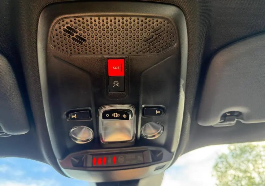 Vue en gros plan du plafonnier intérieur noir du Peugeot e-2008 avec bouton SOS rouge et commandes d’éclairage.