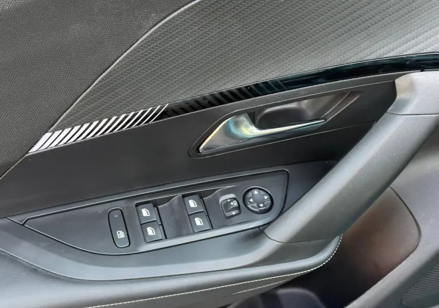 Gros plan sur la porte côté conducteur du Peugeot e-2008 2025, avec commandes électriques et garniture noire.