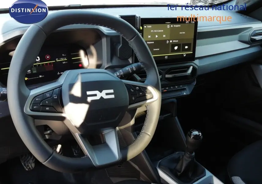 Vue intérieure du tableau de bord et volant du Dacia Duster 2026 gris schiste, avec écran tactile et boîte manuelle.