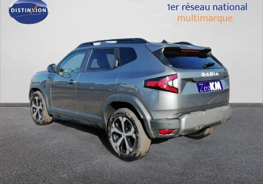 Vue 3/4 arrière droite d'un Dacia Duster gris schiste métal 2026 avec jantes alliage et feux LED distinctifs.