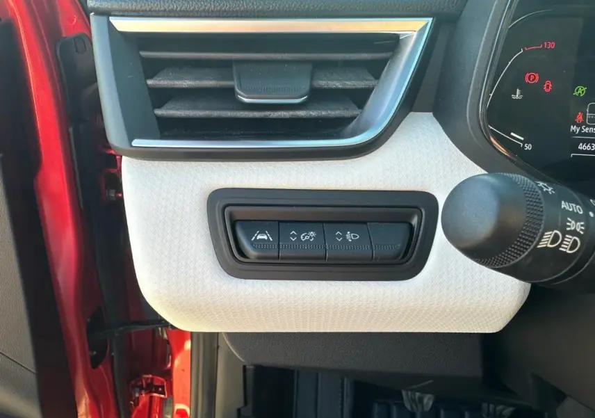 Détail du tableau de bord côté gauche d'une Renault Clio rouge foncé 2021, avec commandes d'aide à la conduite.