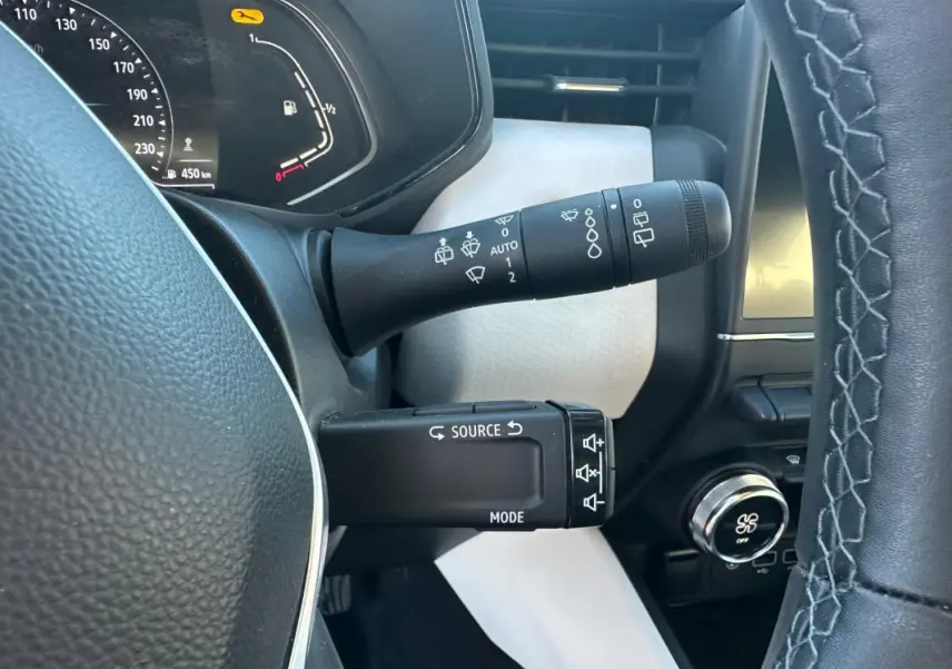 Vue rapprochée du commodo de commandes au volant d'une Renault Clio rouge foncé, version Intens 2021.