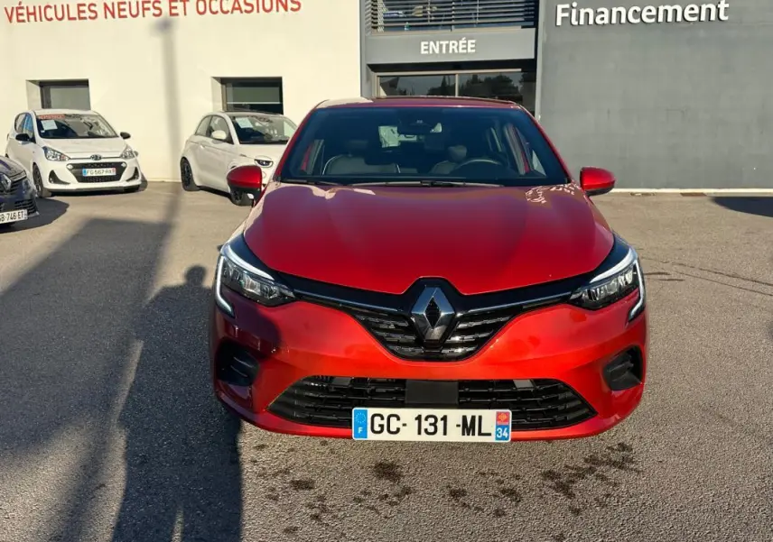 Vue de face d'une Renault Clio rouge foncé 2021 avec calandre noire et logo Renault bien visible.